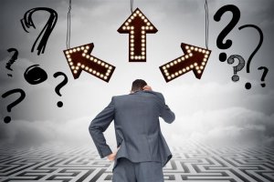 businessman in gray suit with arrows and question marks above him